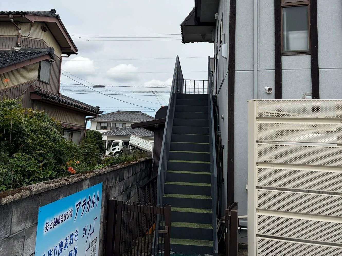 2階へ上がる外階段と、アラカルトの案内看板